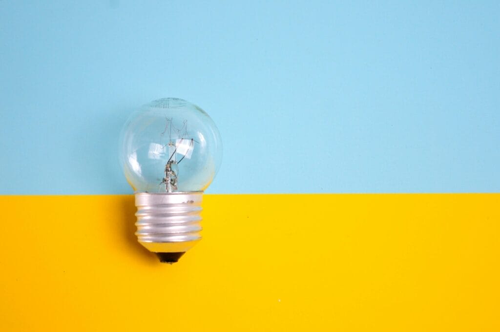 pexels-photo-1495580-1495580 A clear light bulb against a vibrant blue and yellow background, symbolizing energy and creativity.